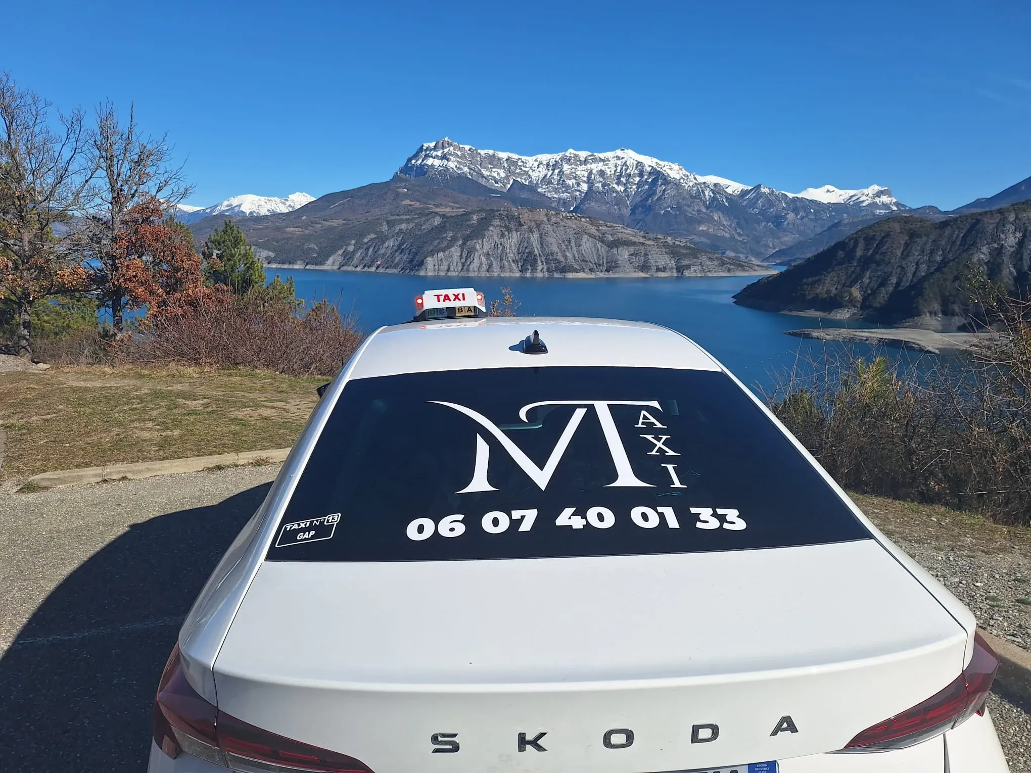 Le taxi Mtaxi face au lac de Serre-Ponçon et aux sommets enneigés