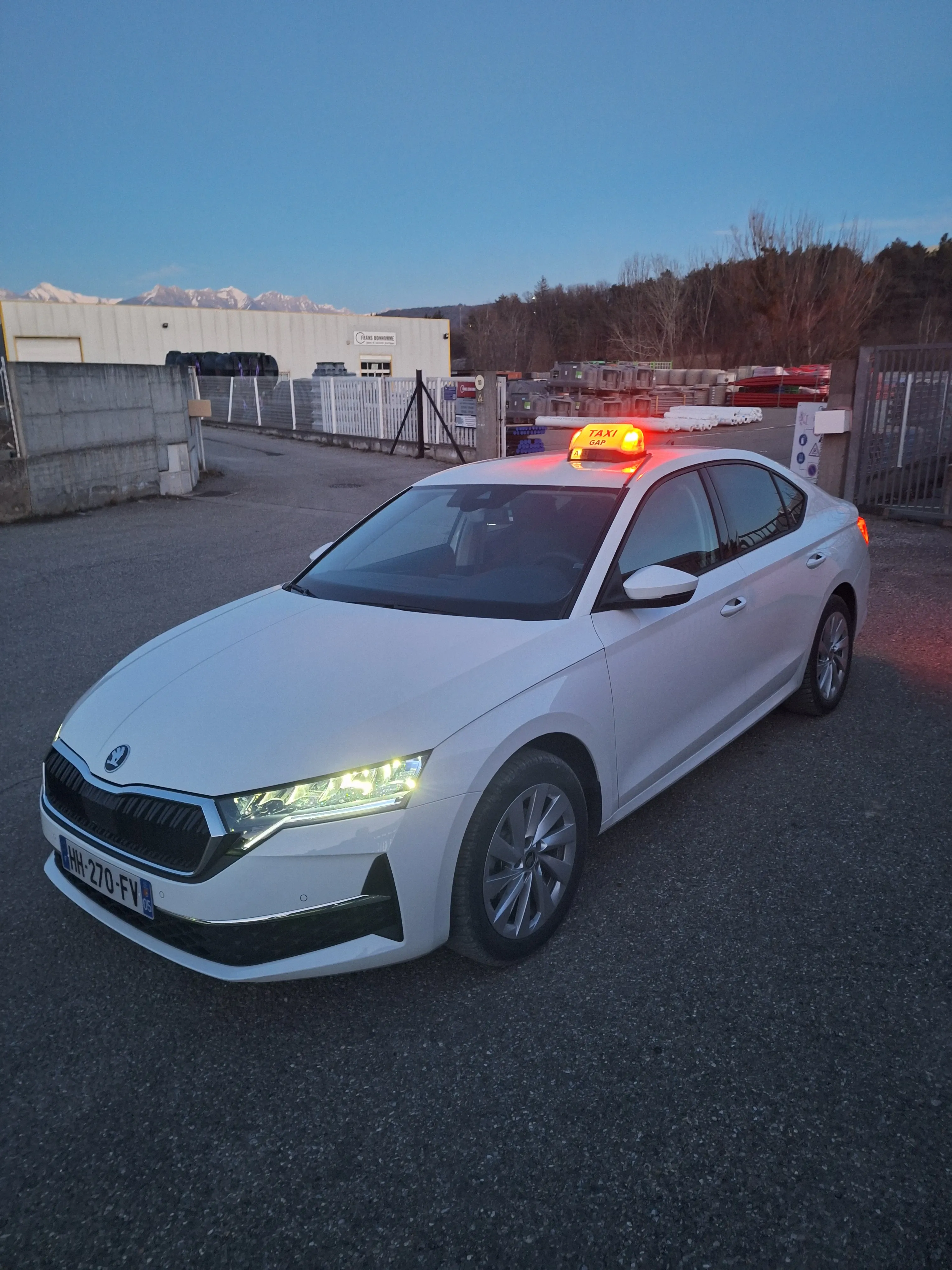 Le taxi Mtaxi, une Skoda Octavia blanche, à l'heure bleue avec les sommets au loin